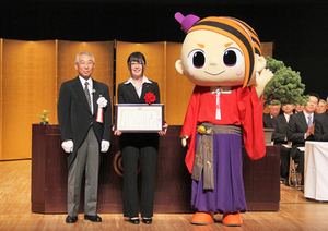 べにのすけと町長とその間に立っている荒井さんの写真