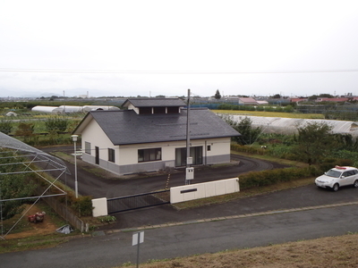 草木が生えた開けた場所に三角屋根の一軒家が立ってる写真