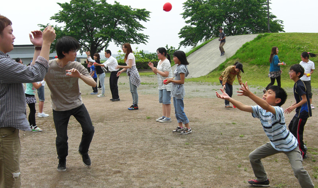 大勢の大人と子供がグラウンドで遊んでいる写真