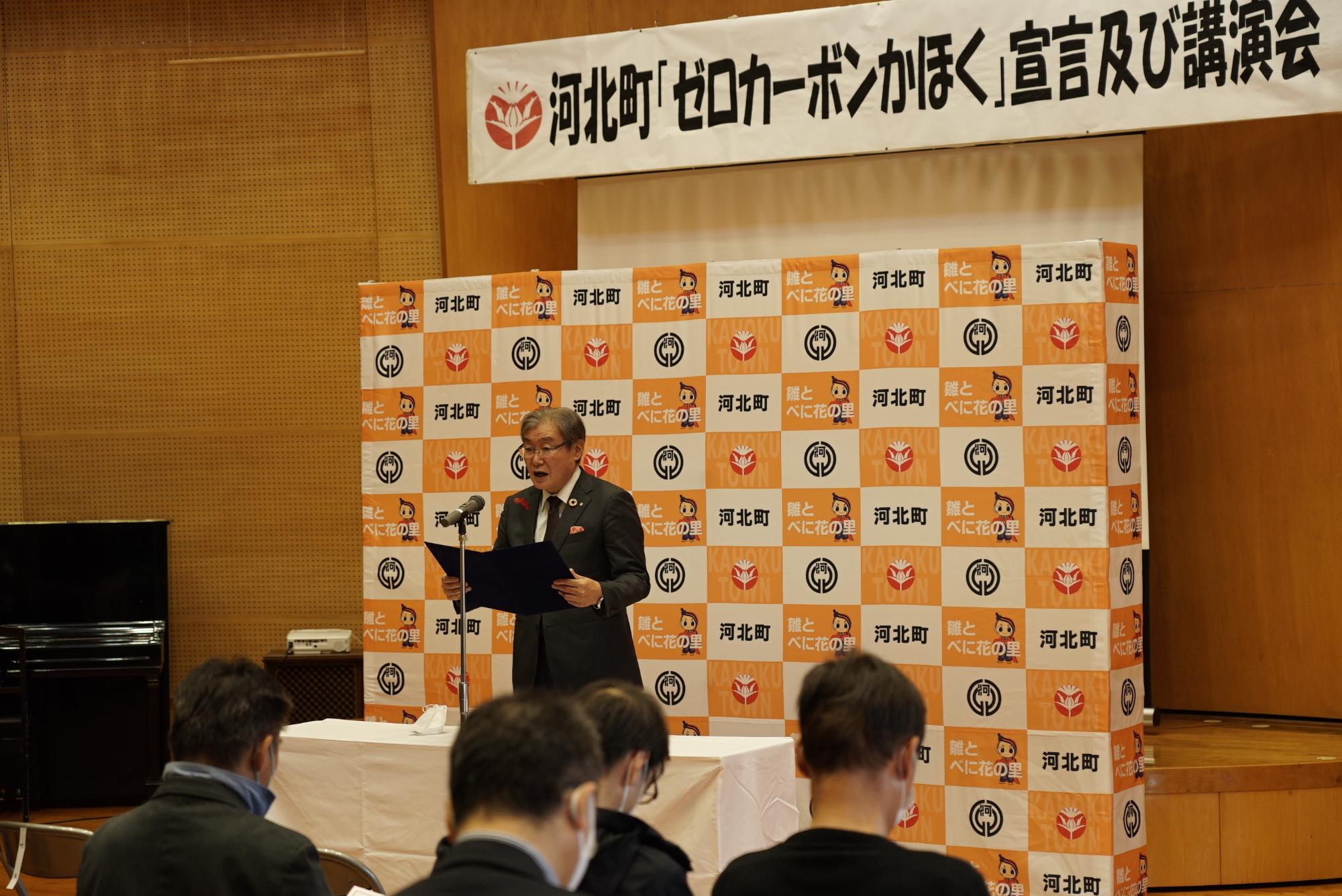 河北町「ゼロカーボンかほく」宣言及び講演会と書かれた題目の下で一人の男性が数人の人の前でマイクで話している写真
