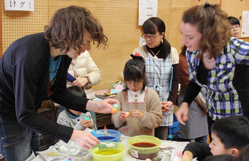 大人と子供たちが机で作業している写真