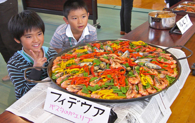 フィデウアというエビをふんだんに使用した料理を目の前に笑顔を浮かべる子供達の写真