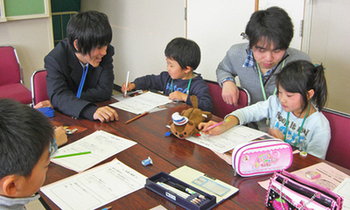 男性2人が子供たちに楽しく勉強を教えている写真