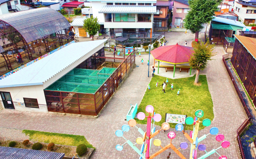 河北町児童動物園を俯瞰して園全体を撮影した写真。屋根付きのベンチや芝生、動物たちのハウスが見える。