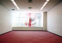 壁の大きな窓から螺旋階段が見える床が赤いカーペットの部屋の写真