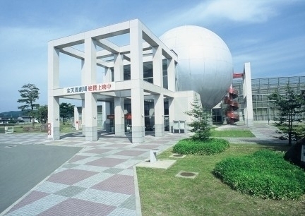 エントランスが正方形で建物に球体のデザインがある白い外壁の建物の写真