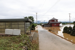 民家が泥水で地面が見えないほど浸水している写真