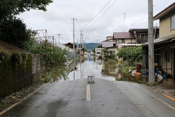 住宅が並ぶ間の道路が一部浸水している写真