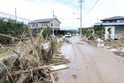 道路が泥で埋め尽くされており道路の端に木の枝などがまとまっている写真