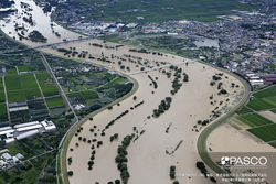 町と町の間の川が氾濫し町の一部も浸水している写真